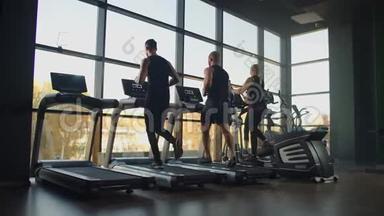 一群人在健身房的跑步机上跑步，进行有氧运动。 男人和女人一起训练